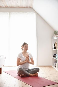 Letting her mind drift peacefully. an attractive young woman doing yoga at home.
