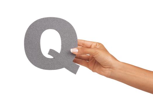 Showing you the letter Q. A young woman holding a capital letter Q isolated on a white background.