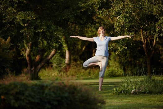 Become like the trees around you. an attractive woman enjoying a yoga session in nature.