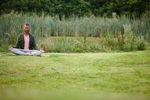 Becoming one with nature. a handsome mature man meditating in the lotus position in nature.