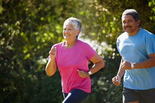 We love keeping healthy together. a mature couple jogging together on a sunny day.