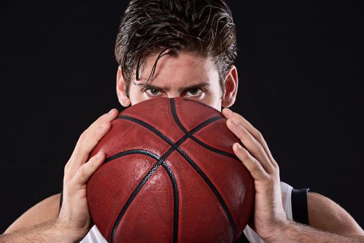 Time to play ball. Cropped studio portrait of a determined basketball player holding the ball out in front of him.