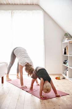 The whole family is into yoga. a young woman and her son doing yoga together at home.