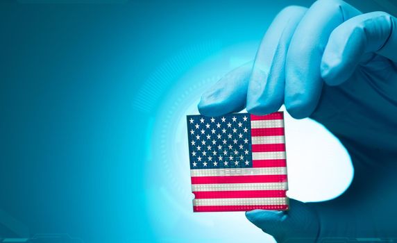 Electronic engineer hand holding computer chip with American flag on blue background. Chipset of electronic circuit board. CPU chip. Computer hardware. Computer processor chip. American computer chip.