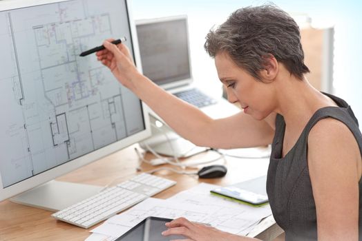 Shes definitely in the right profession. A mature female architect working on building plans on her touchscreen computer.