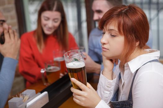 Sad woman drinking beer at the pub