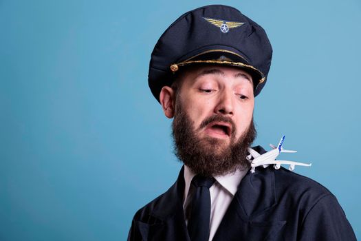 Funny pilot in uniform landing airplane model on shoulder