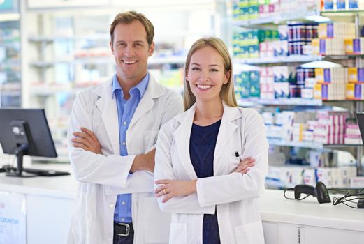 Pharmacists - Here to help. Portrait of two pharmacists standing at the prescription counter.