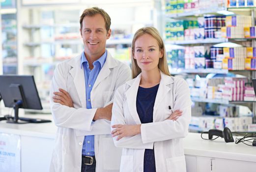 Working together with doctors to ensure your health. Portrait of two pharmacists standing at the prescription counter.