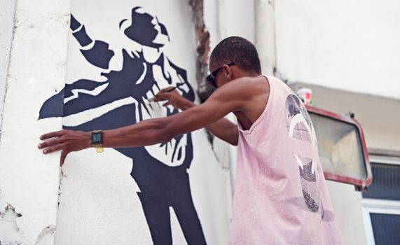 Creative expression. a young graffiti artist painting a design on a wall.