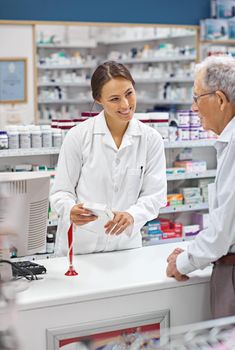She always makes sure customers know their medication. a young pharmacist helping an elderly customer at the prescription counter.