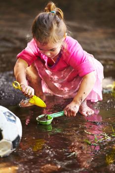 Childhood is all about getting dirty. a little girl playing outside in the mud.