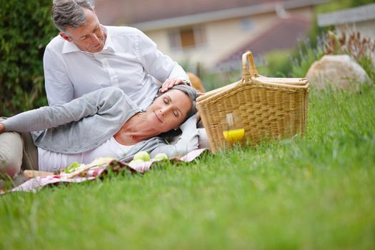 Blissful moments together. a loving mature couple having a picnic on the grass.
