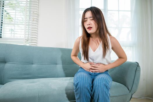 Asian young woman unhappy hands holding on stomach suffering from abdominal pain