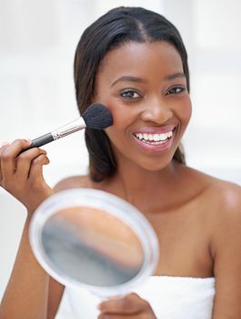 This is the best blush ever. a beautiful young woman applying blush with a makeup brush.