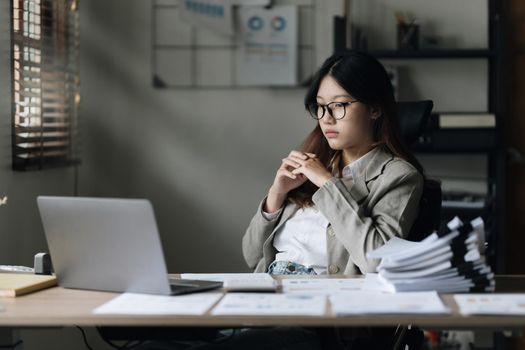 Stressed Asian business woman worry with many document on desk at office