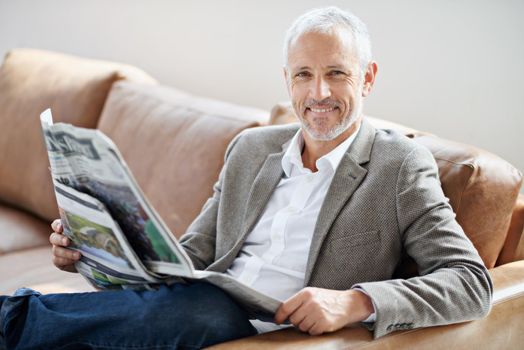 His Saturday morning routine. Portrait of a handsome mature man relaxing with the newspaper on the sofa.