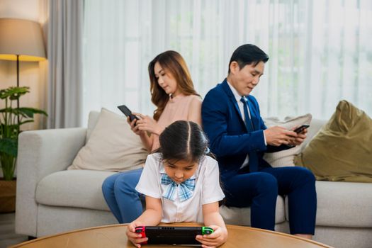 Asian parents ignore their child and looking at their mobile phone at home