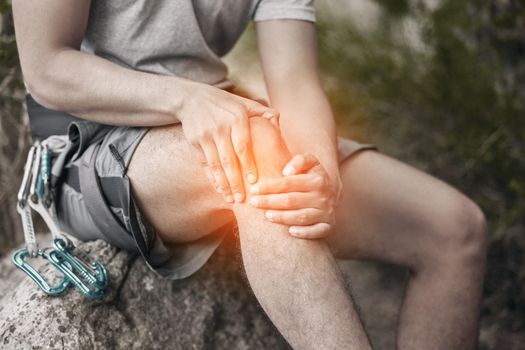 Knee, injury and pain with a man sitting on a rock to take a break while out hiking, rock or mountain climbing in nature. CGI of discomfort from cramp during exercise or sports training in a forest