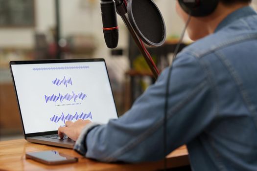 Podcaster editing audio podcast working at home studio