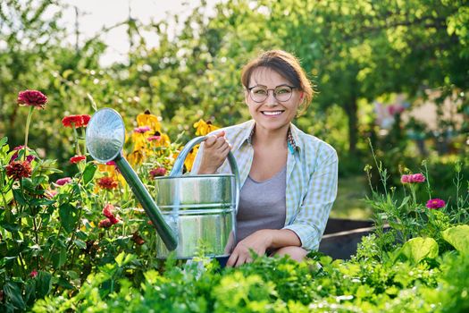 Woman with watering can in vegetable garden in summer season