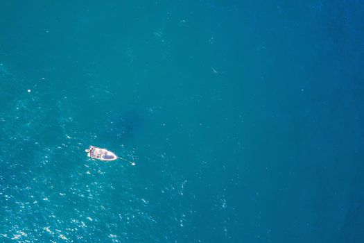 top view of a white boat anchored in the blue sea