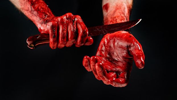 A faceless man in the blood cuts his veins. Black background.