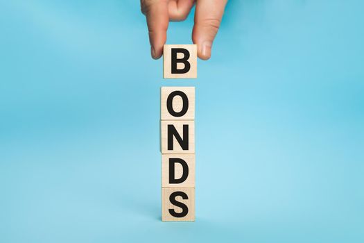 Concept of bonds. Businessman puts wooden blocks with the word Bonds. Equivalent loan. Unsecured and secured bonds. Bonds increasing concept. Copy space.