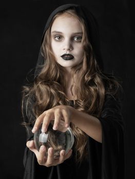Girl in Halloween witch costume with crystal ball