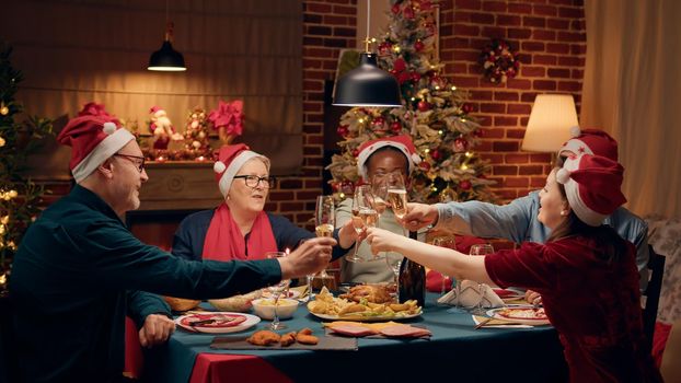 Happy family wearing festive hats gathered home sitting at Christmas dinner table together
