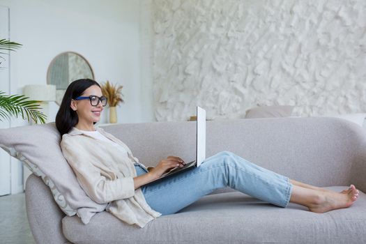 Online work. Young business woman in glasses, freelancer working at home on laptop