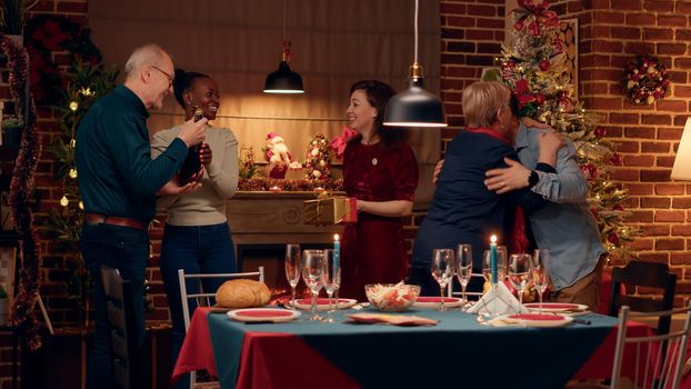Joyful interracial couple welcoming guests to Christmas dinner at home