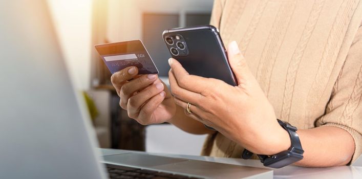 Woman hands holding credit card and smartphone with product purchase at home