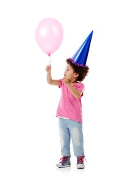 I wonder if I could float away on this thing...Studio shot of a cute little girl wearing a party hat and holding a balloon against a white background.