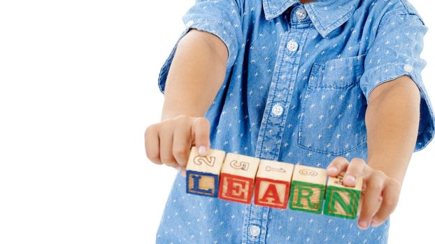 Learn. Thrive. Become. Cropped studio shot of a little boy holding building blocks that spell the world learn against a white background.