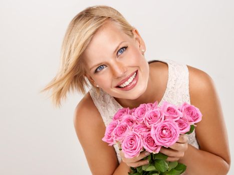 Loving her new flowers. An attractive young woman with an arrangement of pink roses.