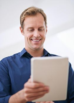 Online chuckles. a handsome man using his tablet at home.