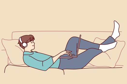 Happy man lying on couch with laptop
