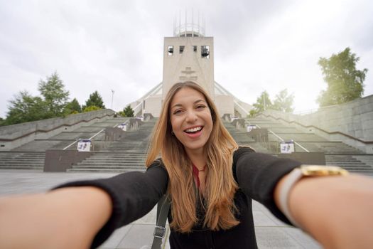 Beautiful young woman taking selfie photo in front of Liverpool Metropolitan Cathedral in England, UK