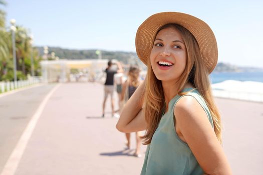 Close-up of stylish girl turns around and looks back on Promenade des Anglais, Nice, France