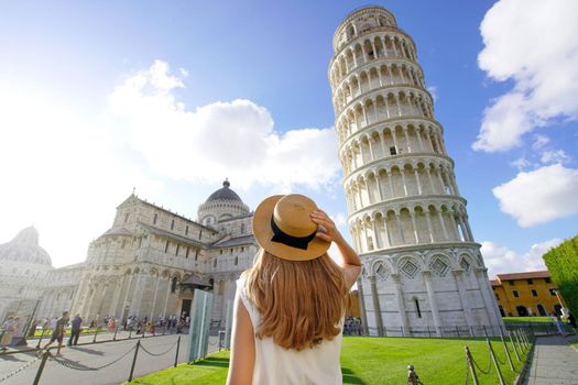 Visiting the Leaning Tower of Pisa, famous landmark of Italy. Young traveler woman in Piazza del Duomo square in Pisa, Tuscany, Italy.