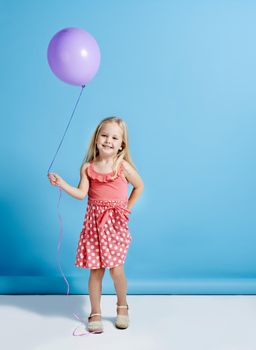 Nobody can be uncheered with a balloon. a cute little girl holding a balloon over a blue background.