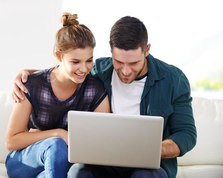 The modern couple. a happy young couple using a laptop while relaxing at home together.