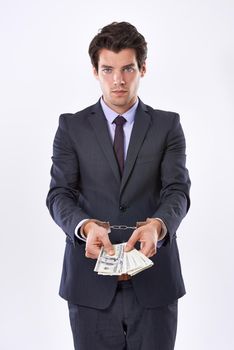 Can money buy my freedom. Studio shot of a handsome young businessman in handcuffs holding American Dollars.