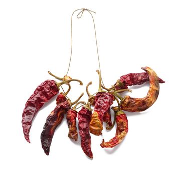 Dry red chili pepper strung on a rope, white isolated background