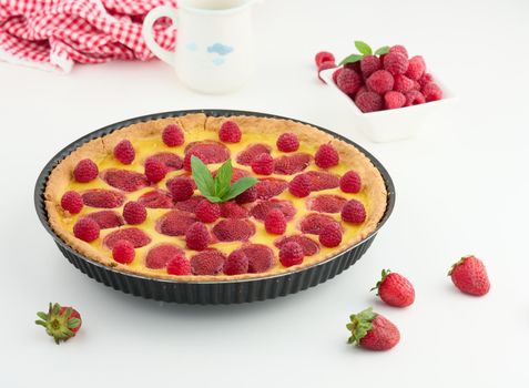 Round quiche with red strawberries and raspberries on a white table