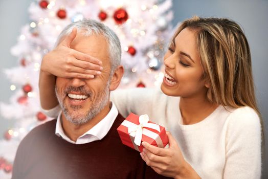 I got you a little something. a young woman surprising her father with a Christmas present.