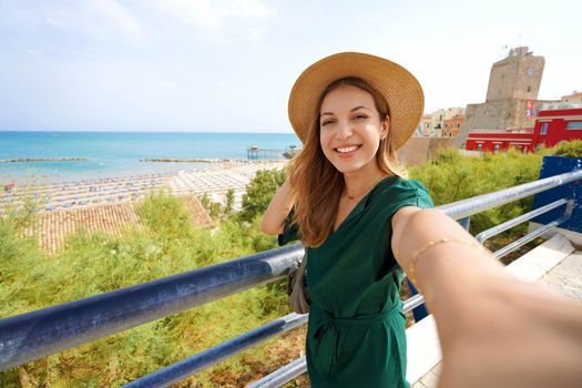 Young beautiful woman smiling happy takes selfie by smartphone camera in Termoli village, Italy