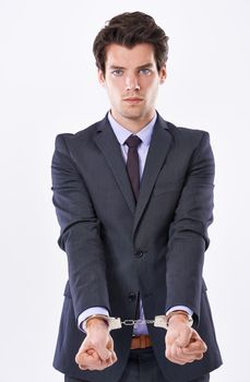 Bound to his business. Studio shot of a handsome young businessman in handcuffs.