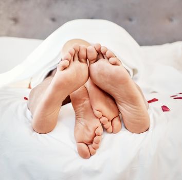 Intimate couple bare feet in bedroom for love, valentines day and sexual partner with passion at home. Closeup of erotic man, woman and foot for morning intimacy, relax marriage and sleeping together